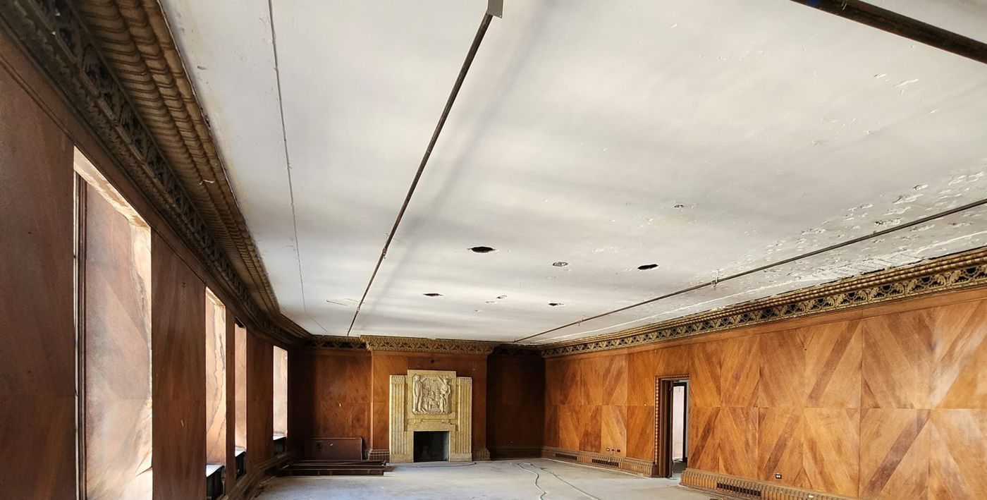 A long wood-paneled hall with a carved cornice and a stone fireplace at the far end