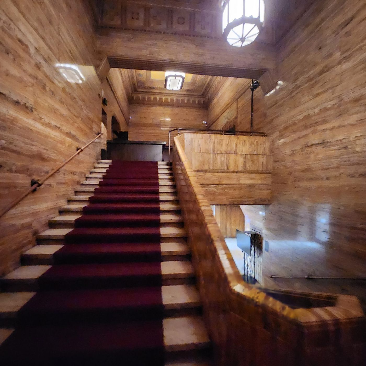 The grand stair with red carpet and wood-paneled walls